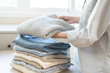 Feel softness, chore of asian young woman, girl housewife hand folding clean clothes after washing, laundry and dry, holding pile, stack clothing from table working at home. Laundry maid in household.