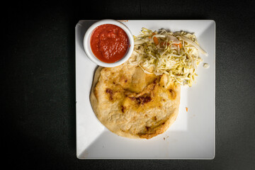 Central American griddle cake with salad and sauce on the side