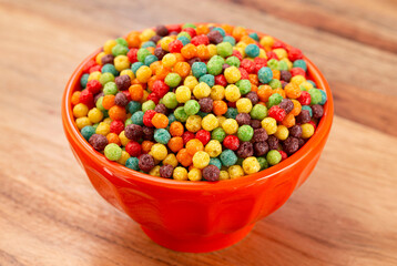 A Bowl of Small Ball Shaped Fruit Flavored Breakfast Cereal on a Wooden Kitchen Table