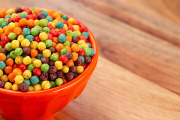 A Bowl of Small Ball Shaped Fruit Flavored Breakfast Cereal on a Wooden Kitchen Table