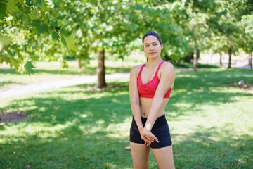 A young woman in athletic wear enjoys a workout in the park, embodying dedication to fitness in a green, sunny setting