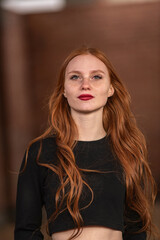 Fototapeta premium Portrait of a young beautiful red-haired girl in dark clothes outdoors.