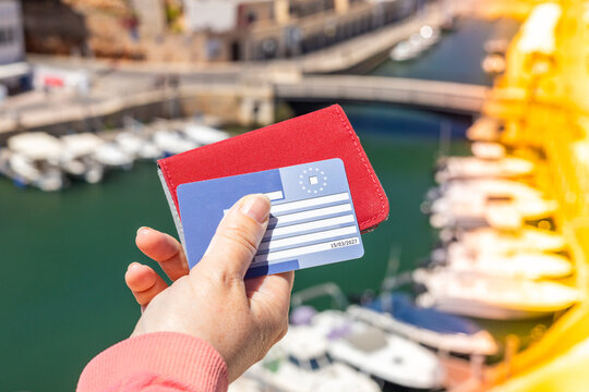 A woman holds in her hand a European health insurance card, useful when traveling within the European Union and EFTA countries, allowing treatment on the same terms as residents of a given country