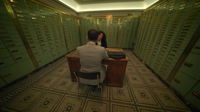 A corporate meeting takes place in a bank vault filled with safety deposit boxes