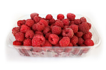 raspberries in a plastic tray on a white