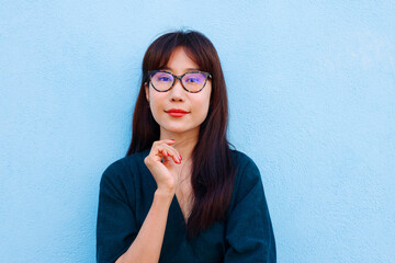 Happy Asian Woman Smiling With Eyes Closed And Glasses Over Light Blue Background