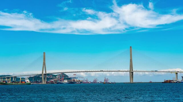 Time-lapse photography of a bridge in Busan. Clouds look lumpy under the blue sky and disappear, and cars pass by on the bridge