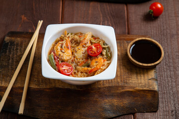 shrimp udon yaki soba sauce on a wooden stand next to soy sauce and chopsticks
