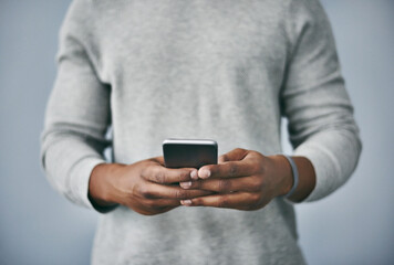 Hands, typing and man with phone in studio for email, contact or text on internet connection. Scroll, smartphone and person on mobile app for online chat, social media or web post on grey background