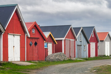 A row of traditional rorbuer huts, painted in vibrant colors with contrasting doors and roofs. Concept: traditional huts, cultural heritage, costal landscape.