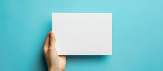 Obraz premium Hand holding blank paper on blue background