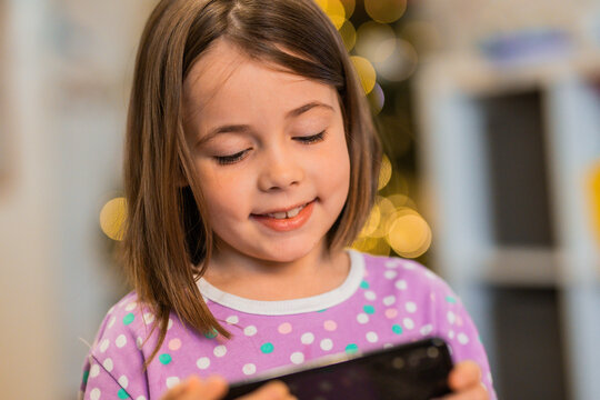 Child looks at smartphone at Christmas time at home. Children and technology.