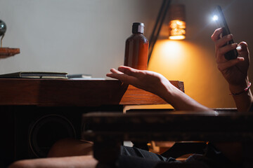 Person using smart phone flashlight to illuminate bottle on desk