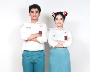 Couple of Indonesian high school students in gray and white uniforms smiling confidently standing with folded hands isolated on white background.