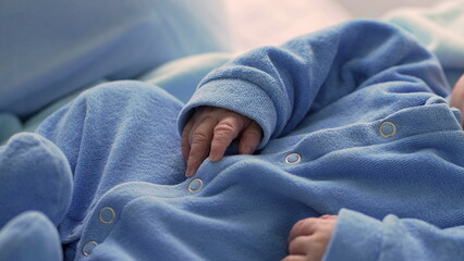 Close-up of a newborn baby peacefully sleeping in a blue onesie, highlighting the delicate features...