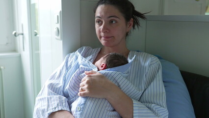 Mother’s hands carefully adjusting newborn baby’s clothing in a bassinet, viewed through crib...