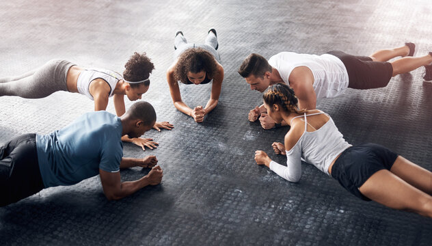Class, fitness and plank in group at gym for workout, core exercise or training together indoors. Diverse people, friends and warm up for ab muscle, session and sport for health on gymnasium floor