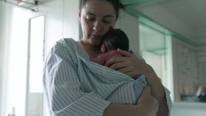 Mother tenderly kissing newborn baby’s head, wrapped in a striped hospital gown, capturing the intimate and loving bond, emphasizing maternal affection and the peaceful moments of early motherhood