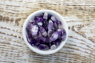 Set of various amethyst natural mineral stones and gemstones on black plate and grey background