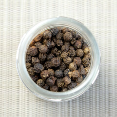 Pile of Black peppercorns Black pepper dried seeds on glass plate wooden background
