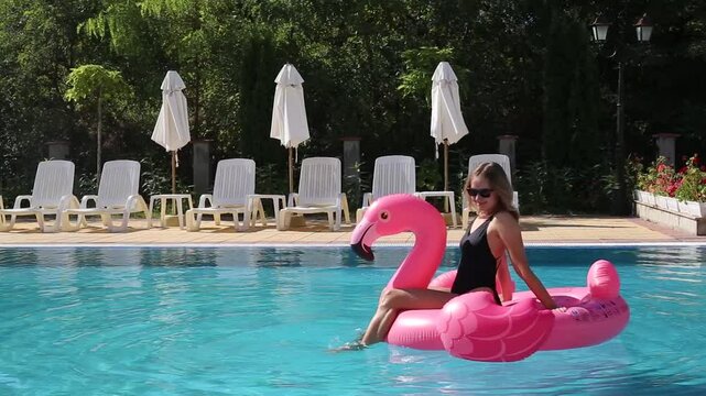 Beautiful woman on flamingo pool float and unicorn in pool. Summer holidays
