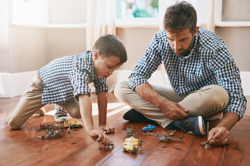 Father, son and playing with toys on floor for bonding, activity or imagination at home. Playful dad with young child, kid or little boy with action figures, solidiers or cars for fun games at house © Sanc/peopleimages.com