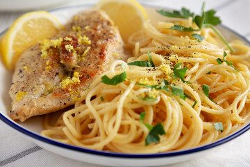 Homemade Lemon Pepper Chicken with Spaghetti Pasta on a Plate, side view. Close-up.