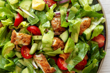 Homemade Crispy Chicken Salad with Tomato and Cucumber on a Plate, top view.