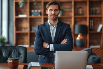 A confident man stands in an office environment with his arms crossed, holding a determined expression while standing in front of a laptop and a coffee cup on a wooden desk.