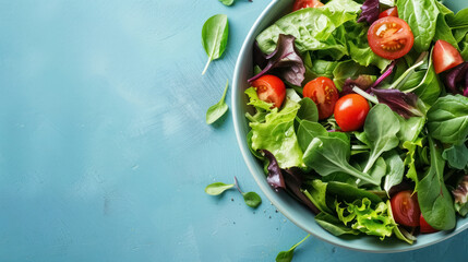 fresh organic mixed salad with tomatoes in a bowl on blue background