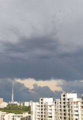 the sky in bad weather, gray clouds over the city, a rainbow among the clouds