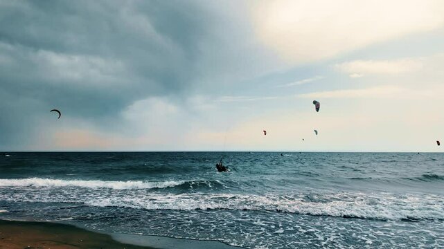 People surf with Kyte surfers on the sea waves in summer near people bathing. Extreme sports and outdoor life. Warm holiday with wind on the sea High speed and adrenaline. Strong wind