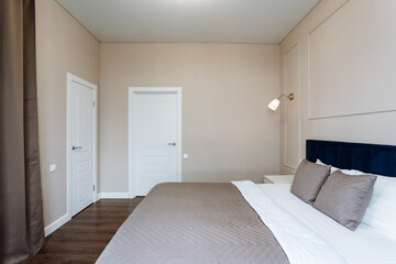 The bedroom features a highend kingsize bed, a private door, and stylish fixtures. Its a comfy space with lovely hardwood flooring, providing a relaxing retreat for guests