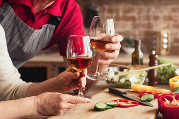 A couple is seen enjoying a glass of wine after preparing a meal in their kitchen. They are both...