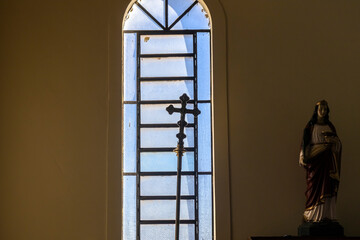 Silhouette of a crucifix used by the Catholic church for masses leaning against a glass window with the background against the light in Brazil