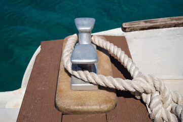Obraz premium Loop of white spiral rope around steel anchor on boat. Mooring rope used for securing the ship to the harbour. Elements of ship and boat equipment