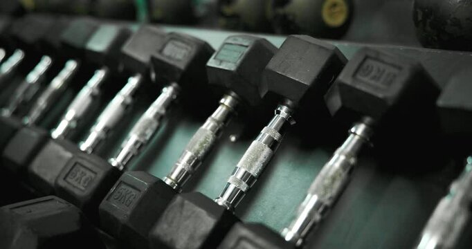 Equipment, metal and dumbbell in gym for sports, weightlifting and strength training for power. Closeup, exercise and workout with resistance tools, iron and steel in row for wellness in health club