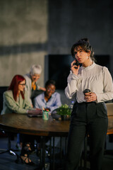 Businesswoman talking on a phone during meeting of interracial team.