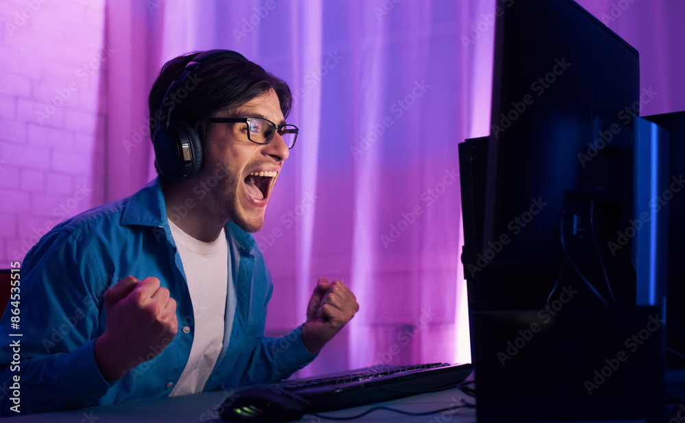 Poster a young man wearing headphones and glasses is seated in front of a computer screen playing video gam