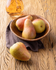 Red pears in a bowl with rose wine over wooden table