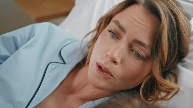 Lying woman reading book for daughter at bedroom closeup. Mom child relaxing