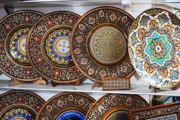 handmade Uzbek wooden souvenir plates with wood carvings hand-painted asian patterns in bazaar of Uzbekistan in Tashkent