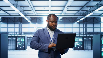 Computer scientist in data center using diagnostic tools and system monitoring software on laptop...
