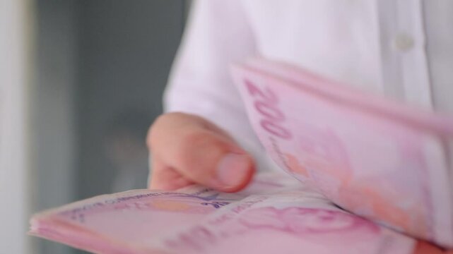man in white shirt counting Turkish lira coins in his hand in close-up