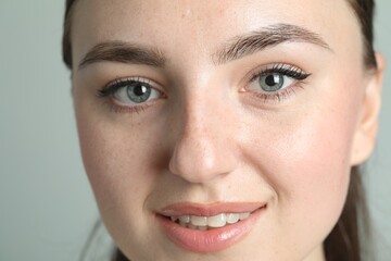 Young woman with beautiful eyebrows on light background, closeup