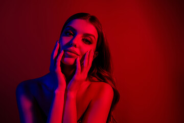 Portrait of stunning young lady touch face empty space bare shoulders isolated on neon red blue background