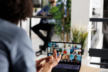 Arab entrepreneur leading virtual meeting with startup team in videocall on laptop. Professional discussing business plan with colleagues through video conference in corporate coworking space