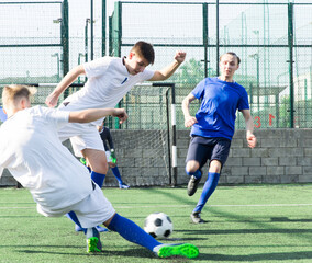Obraz premium Young football players fighting for ball in middle of field