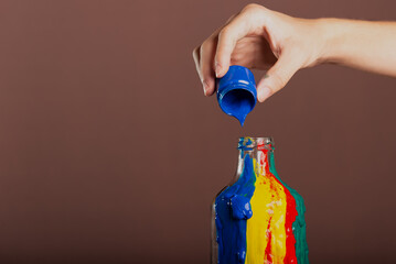 Painters hand pouring blue paint into a glass bottle. abstract art.