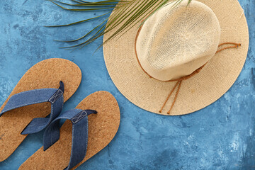 Pair of flip flops with hat and palm leaves on grunge blue background